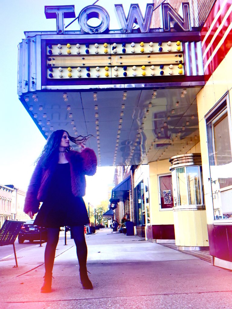 Bellatryx wearing pink fuzzy coat and pink dress with boots in front of movie theater 